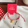 Detail of red braided bracelet with pink glass beads and golden zodiac charm on canvas - Gold Zodiac Dog Pink Beaded Bracelet