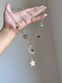 Dettaglio della collana dorata con stelle e luna, zirconi e gemme colorate lucenti - Oro