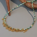 Handmade turquoise beaded necklace with gold fringe tassel on rustic wood background - Turquoise With Metal Tassel