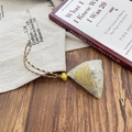 Macro-opname van een driehoekige zongzi-hanger met vintage jacquard op houten decor - Pastoraal Geel