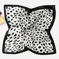 Detail of a square silk scarf with black and white polka dot patterns in a spiral fold - Cow Print