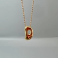 Macro shot of gold bean pendant on a fine O-chain necklace with smooth polished finish - Letter D Single Pendant