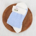 Chaussettes thermiques épaisses bleu clair et blanc en peluche sur un tapis tressé - Bleu clair