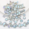Detalle macro de cuentas de vidrio irisadas de luna y estrella para joyería DIY - Verde Transparente
