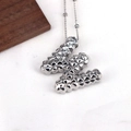 Macro shot of silver letter W pendant with rivet texture on a minimalist necklace - Letter W