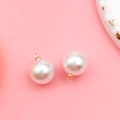 DIY jewelry charm with round white pearl and golden metal loop on pink background - 12mm KC Gold Round