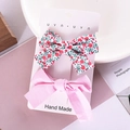 Detailed view of handmade floral and pink fabric bow hair clips on a display card - Pink Floral Set