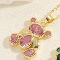 Détail du pendentif ours doré avec des pierres de zircon rose sur un fond texturé blanc - Ours en Zircon Rose