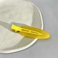 Detailed view of yellow matte finish hair clip on a textured white plate display - Yellow