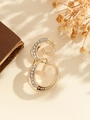 Elegant gold letter E brooch with sparkling rhinestones on textured cream surface - Gold Letter E
