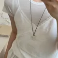 Dettaglio di un ciondolo a fiore in argento su un cordino nero indossato da una modella - 20# Ciondolo Fiore Cavo Minimalista Con Cordino Nero (HN7349)
