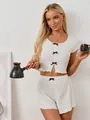 Dettaglio del set pigiama in maglia a coste bianche con delicati fiocchi marroni - S / Bianco
