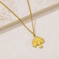 Macro shot of gold tree of life pendant on a textured stone surface with fine link chain - Tree of Life Pendant (NKS-002_07)