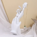 White resin hand jewelry stand displaying gold necklaces and rings on silk fabric - Rose Pose Hand