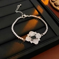 Detailsicht eines silbernen Blumenarmbands mit schwarzem Stein auf schwarzem Display - Silberfarbenes schwarzes Armband