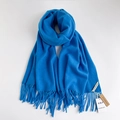 Morbida sciarpa pashmina blu con frange ed etichetta del marchio su sfondo bianco - Acquamarina