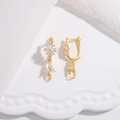 Elegante goldene Blumenohrringe mit weißen Zirkonia auf einem weißen Dekotablett - Gold
