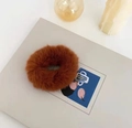 Close-up of soft brown plush scrunchie with fluffy texture on grey backdrop - Caramel color