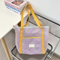 Dettaglio della borsa tote in rete viola chiaro con manici gialli su una sedia - Viola Chiaro