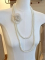 Detail van een dubbellaagse parelketting met een beige stoffen roos als versiering - Ketting-Witte Bloem