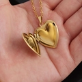 Primer plano de un relicario de corazón dorado abierto para fotos en una mano - 22.6*25mm / Dorado