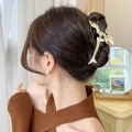 Pince à cheveux dauphin dorée en métal portée par un mannequin dans un décor chaleureux - Pince à Cheveux Dauphin Doré