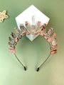 Detail van roze natuurstenen kroon met zilveren zon-, maan- en slangenhangers op de band - Rhodoniet