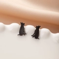Detailed view of matte black German Shepherd silhouette stud earrings on a white plate - Sitting German Shepherd (779) / Black