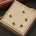 Golden flat snake chain necklace with five emerald green square stones on beige box - Necklace / Gold/Green