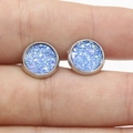 Macro shot of 8mm blue glitter stud earring with silver base held between fingers - Blue (7)