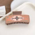 Brown rectangular hair claw clip with vintage geometric pattern on a white tray - Cross