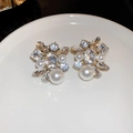 Dettaglio di orecchini argentati con strass scintillanti e perle finte su un piatto bianco - Cluster Ovale (Perno in Argento 925)