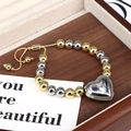 Adjustable two-tone bead bracelet with silver heart charm on a wooden display tray - Silver