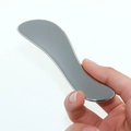 Polished silver heart shaped 304 stainless steel Gua Sha tool being held in hand - S-Shape 115*30*3.5MM