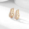 Close-up of golden U-shaped earrings with micro-pave crystals and hollow detailing - White Zirconia