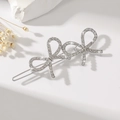 Detailed view of silver bow hair clips with rhinestones and pearls on a white stone surface - Rhinestone Silver
