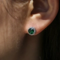 Macro shot of a round halo earring with a deep green gemstone and sparkling white zircons - White Gold with Green Zircon