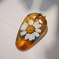 Detalle de colgante de gota en resina con margarita seca y tinte ámbar - Arcoíris