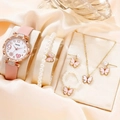 Macro shot of pink butterfly jewelry set with pearl necklace and watch on beige satin - Pink
