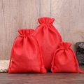 Three sizes of red linen drawstring bags for jewelry displayed on wood background - Red