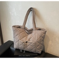 Close-up of khaki quilted tote bag featuring a snap-button front pocket and padded straps - Khaki