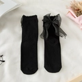 Flat lay of black cotton socks featuring large sheer tulle bows and lace ruffle trim - One Size / Black