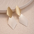 Dettaglio di orecchini geometrici a rombo con finitura in argento spazzolato e oro lucido - Oro Lucido e Argento Spazzolato