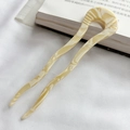 Close-up of beige acetate U-shaped hair pin with white marble texture on fabric background - Off White
