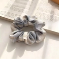 Plaid ribbon scrunchie in grey and beige fabric resting on an open book page - Lemon Sea Salt Gray