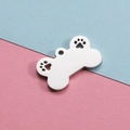 Polished silver dog bone pendant with hollow paw prints on a blue and pink background - Steel