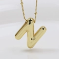 Macro shot of polished gold-tone letter N bubble pendant with a fine bead chain - Letter N (Necklace)