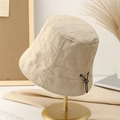 Minimalist beige quilted bucket hat with adjustable cord shown on a metal display stand - M (56-58cm) / Off White