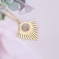 Detailed view of a gold sunburst pendant necklace with a round grey gemstone center - Grey