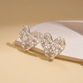 Macro view of silver heart stud earrings with a hollow mesh texture on a modern prop - Silver (925 Sterling Silver Earring Post)